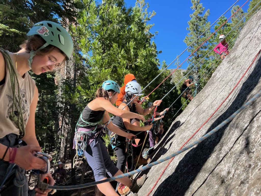 women hanging on the side of a rock face at a self rescue class working on their rope systems