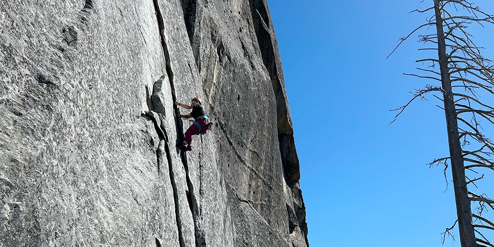 Woman rock climbing granite rock face.